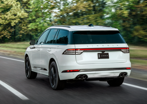 A white 2025 Lincoln Aviator® SUV is being driven away down a road lined with colorful trees. | LaFontaine Lincoln Grand Rapids in Grand Rapids MI