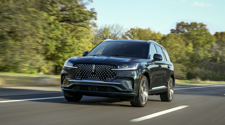 A 2025 Lincoln Black Label Aviator® SUV is being driven down a road lined with trees. | LaFontaine Lincoln Grand Rapids in Grand Rapids MI
