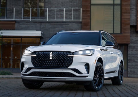 A 2026 Lincoln Aviator® Reserve model is shown with the available Jet Appearance Package parked near a restaurant. | LaFontaine Lincoln Grand Rapids in Grand Rapids MI