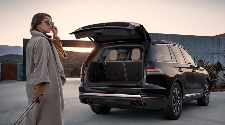 A woman approaches a 2026 Lincoln Aviator® SUV with its rear liftgate open. | LaFontaine Lincoln Grand Rapids in Grand Rapids MI