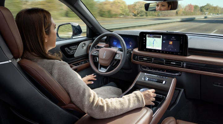 A 2026 Lincoln Aviator® SUV is being driven hands-free on a highway near a forest | LaFontaine Lincoln Grand Rapids in Grand Rapids MI