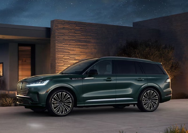 A green 2027 Lincoln Aviator® SUV is parked outside a contemporary home. | LaFontaine Lincoln Grand Rapids in Grand Rapids MI