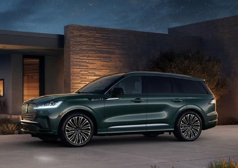 A green 2027 Lincoln Aviator® SUV is parked outside a contemporary home. | LaFontaine Lincoln Grand Rapids in Grand Rapids MI