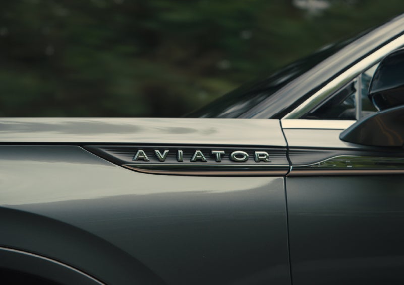 The driver’s side door and fender badging of a gray 2027 Lincoln Aviator® SUV are showcased. | LaFontaine Lincoln Grand Rapids in Grand Rapids MI