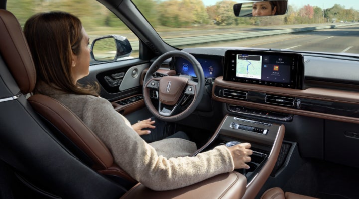 A 2027 Lincoln Aviator® SUV is being driven hands-free on a highway lined with trees. | LaFontaine Lincoln Grand Rapids in Grand Rapids MI