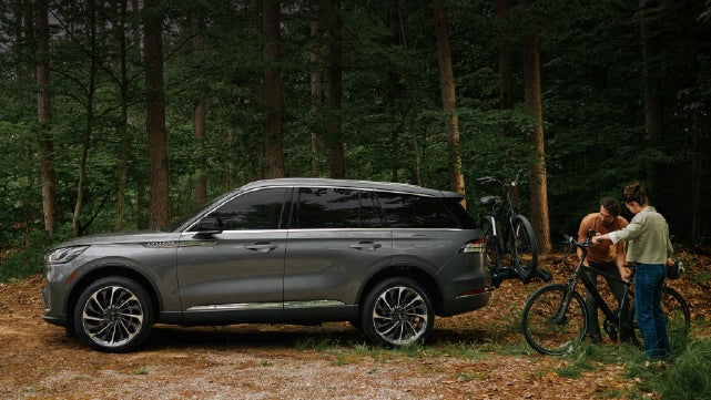 A father and son load e-bikes on a bike rack attached to a 2027 Lincoln Aviator® SUV. | LaFontaine Lincoln Grand Rapids in Grand Rapids MI