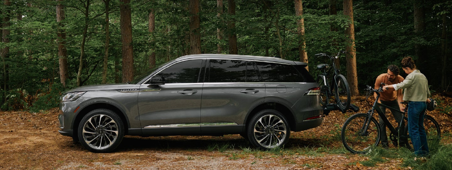 A father and son load e-bikes on a bike rack attached to a 2027 Lincoln Aviator® SUV. | LaFontaine Lincoln Grand Rapids in Grand Rapids MI