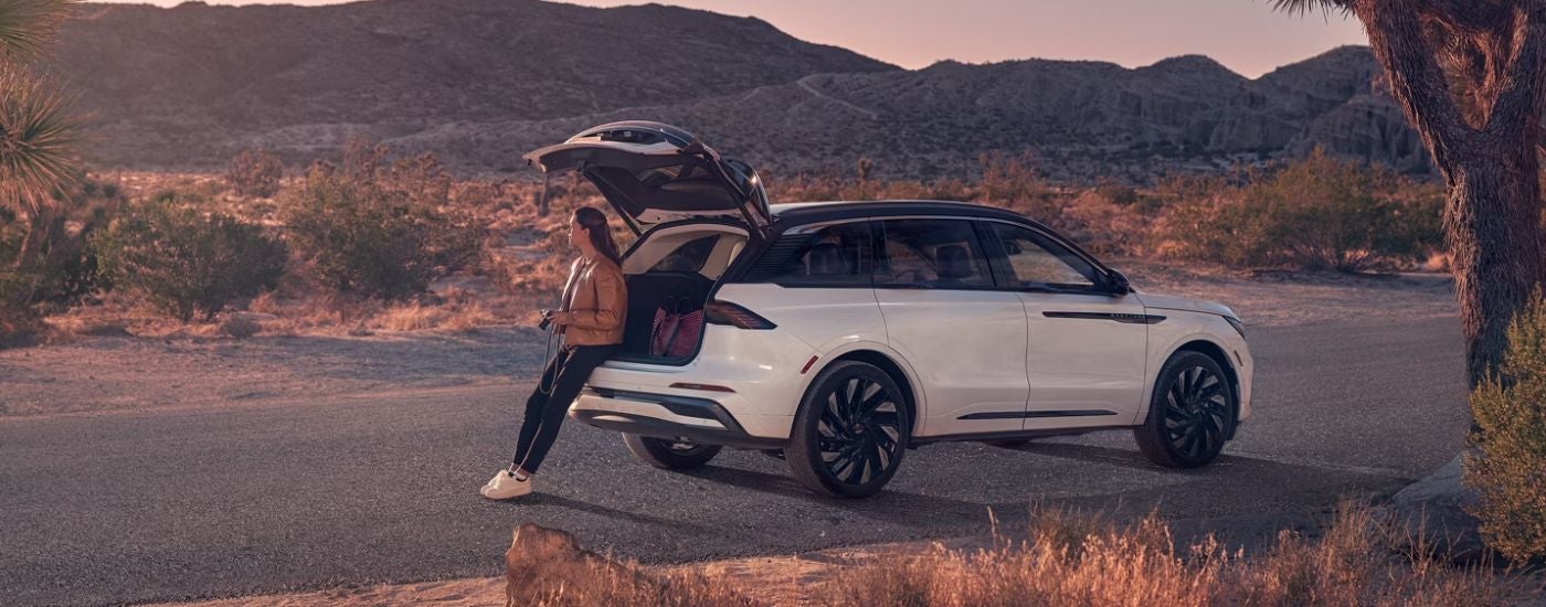 A woman sitting in rear cargo area of a white 2026 Lincoln Nautilus.