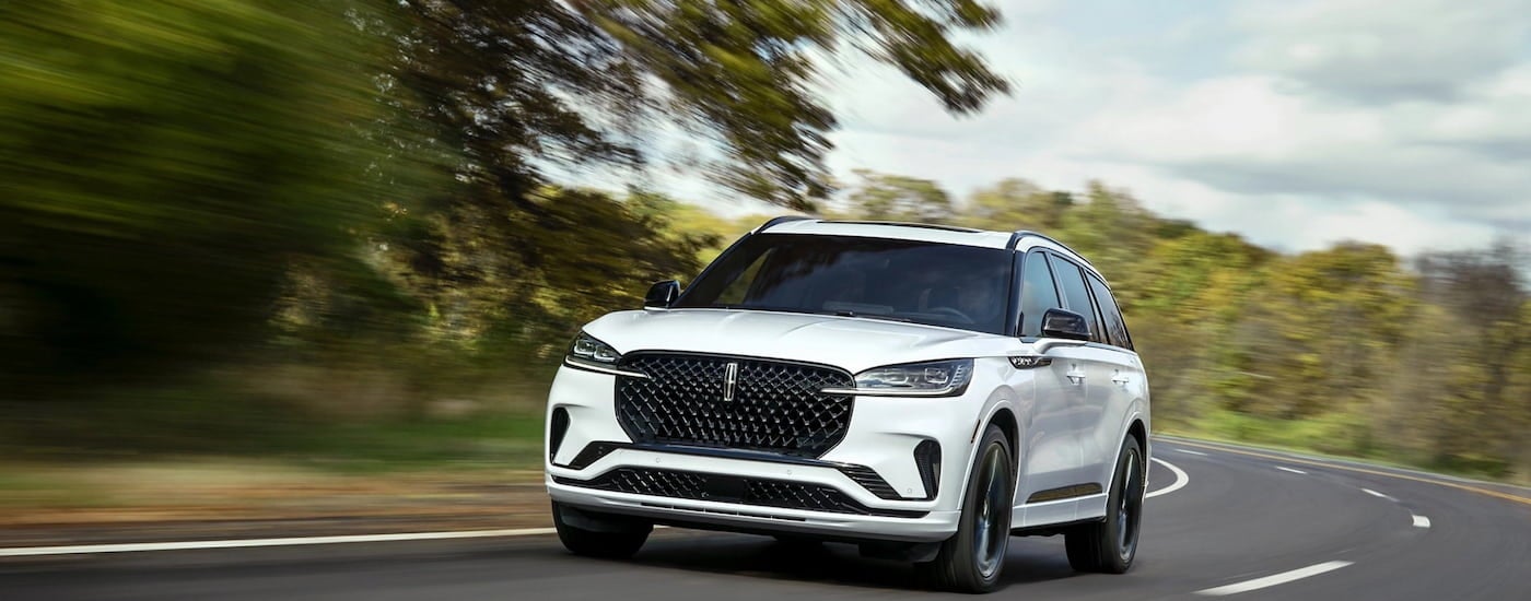 White 2026 Lincoln Aviator driving down a winding road.