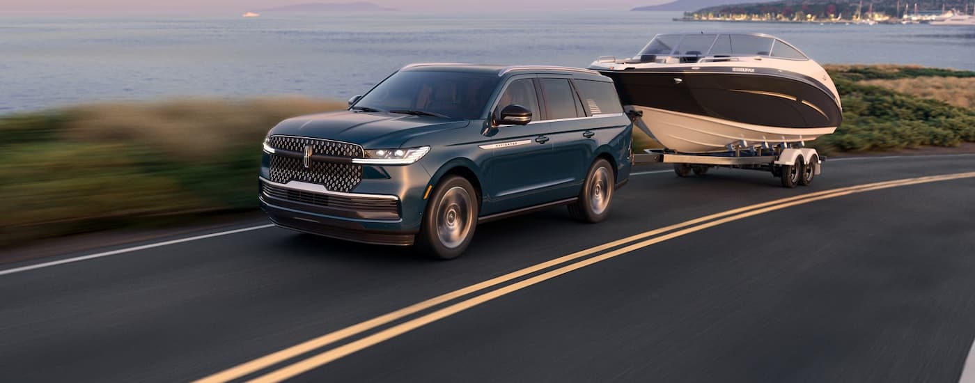 Dark blue 2023 Lincoln Navigator towing a boat down a road.
