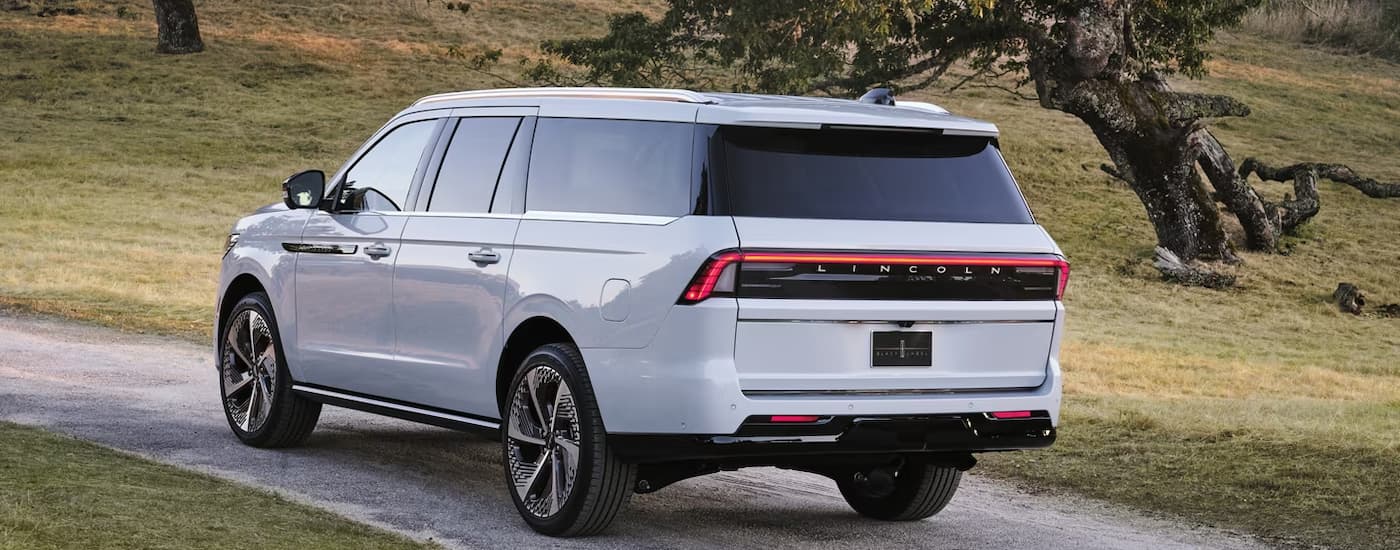 Rear of a white 2025 Lincoln Navigator driving down a road.