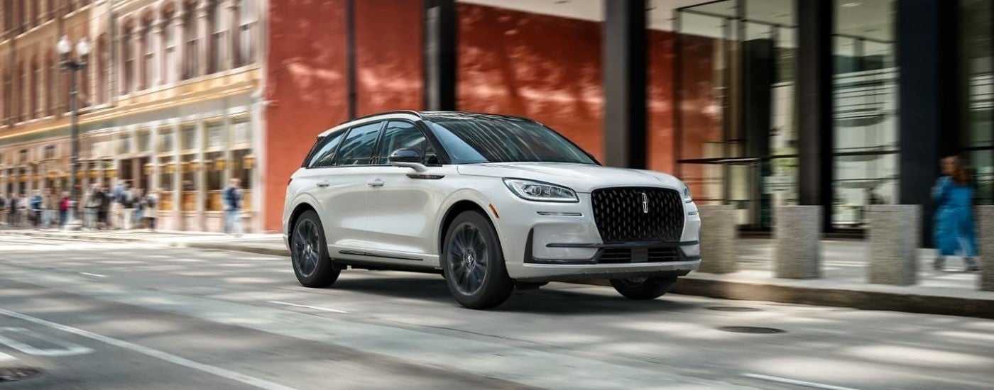 White 2026 Lincoln Corsair driving down a city street.