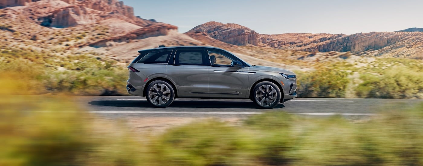 Side of a grey 2026 Lincoln Nautilus driving down a road.