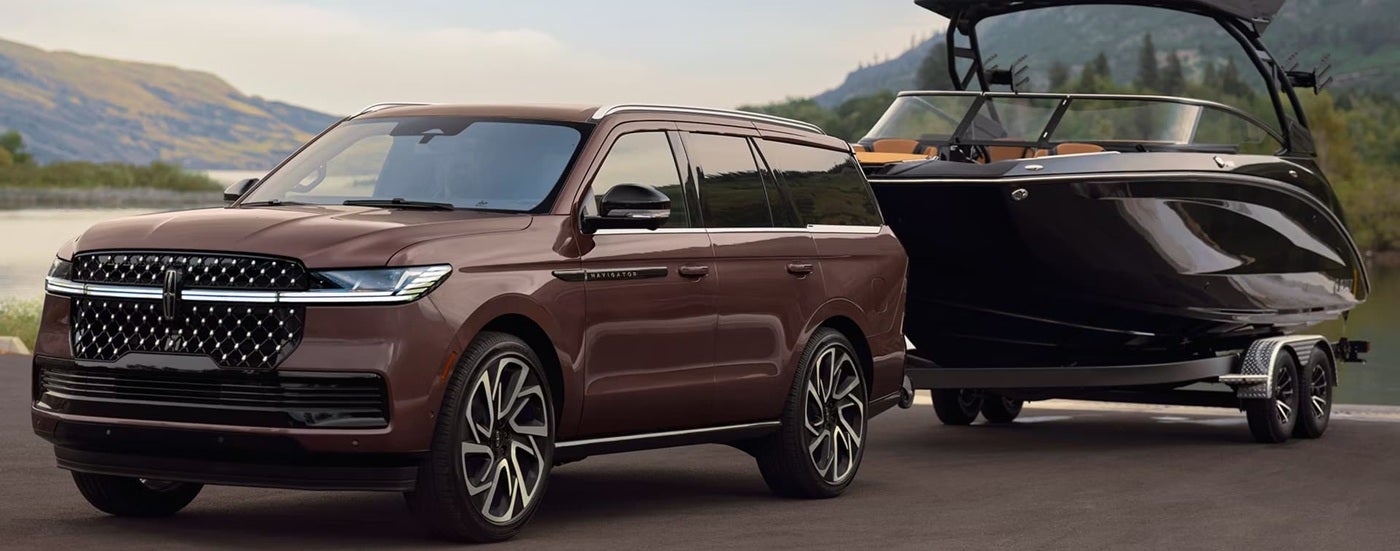 Brown 2026 Lincoln Navigator towing a boat down a road.