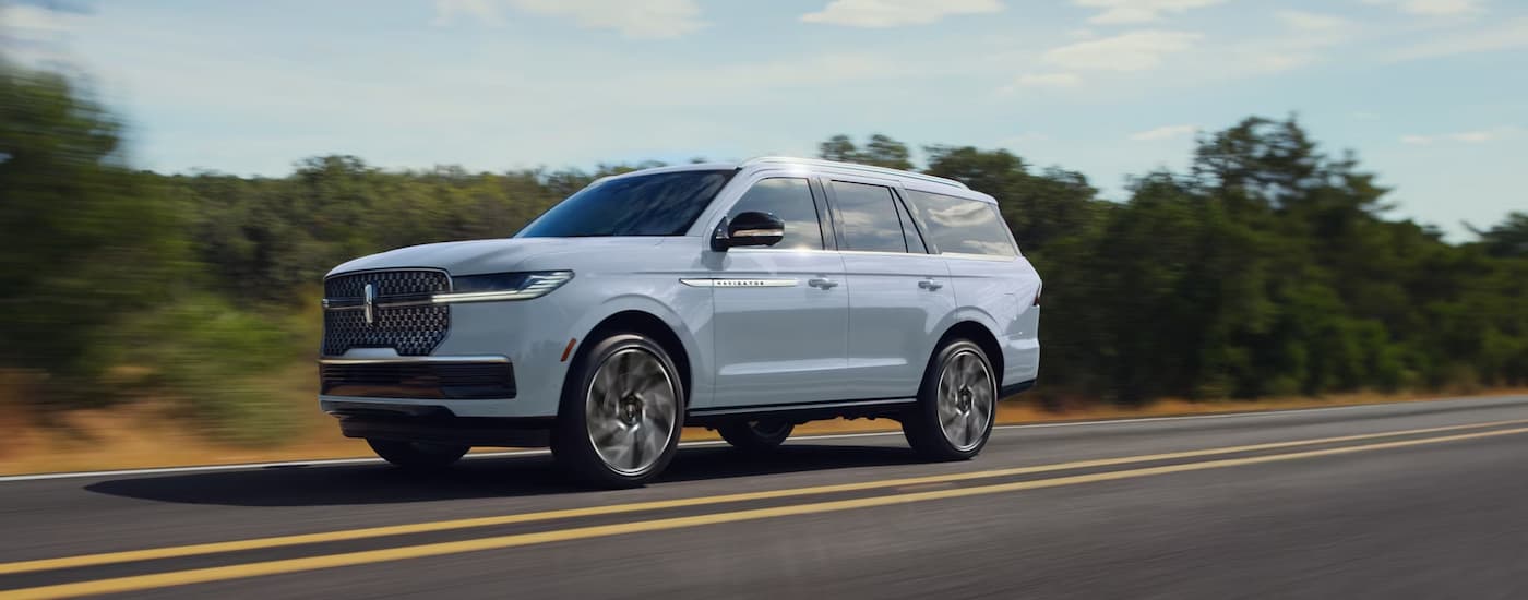White 2026 Lincoln Navigator driving down a road.