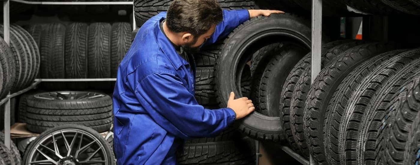 Mechanic lifting a tire onto a shelf of tires.